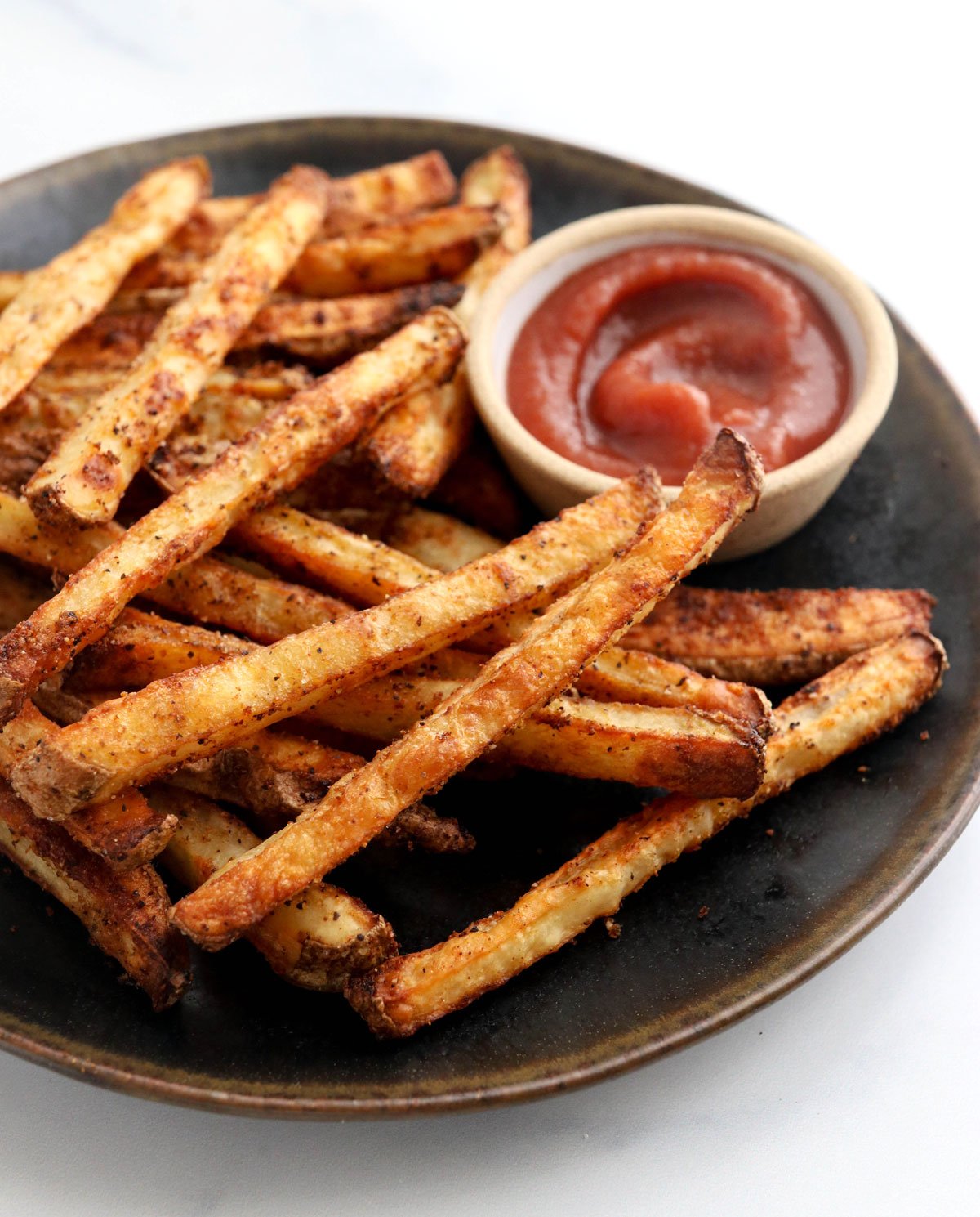 baked french fries on black plate with ketchup