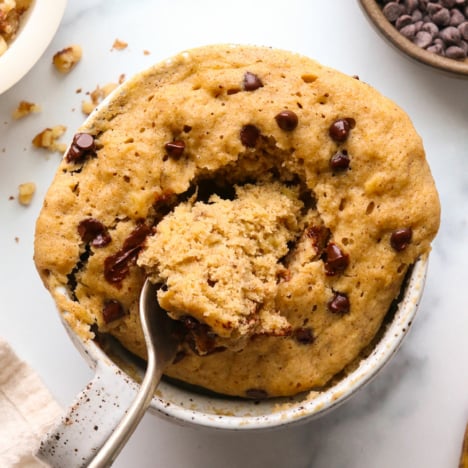 banana mug cake with a fork in the middle to show the fluffy center texture.