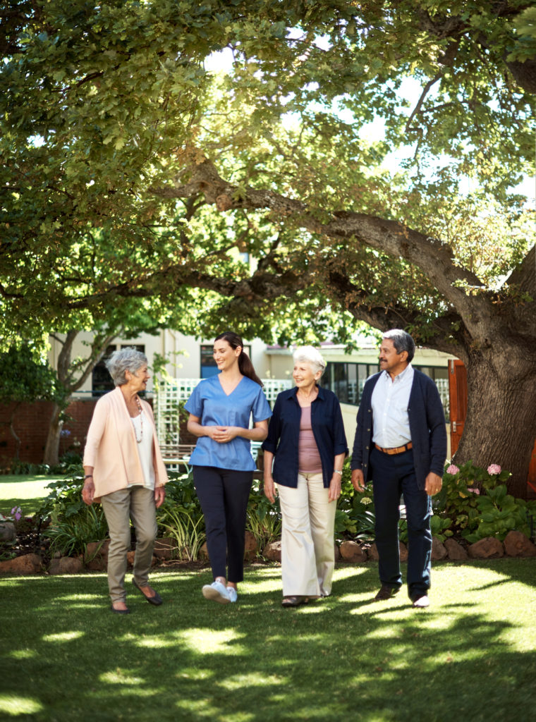 Shot of seniors going for a walk in the garden with a young nurse