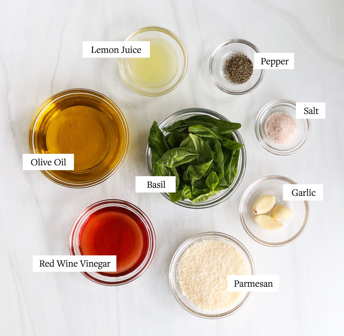 pesto dressing ingredients labeled in glass bowls.