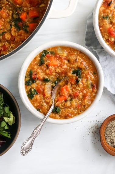 Quinoa soup in a white bowl with a spoon inside