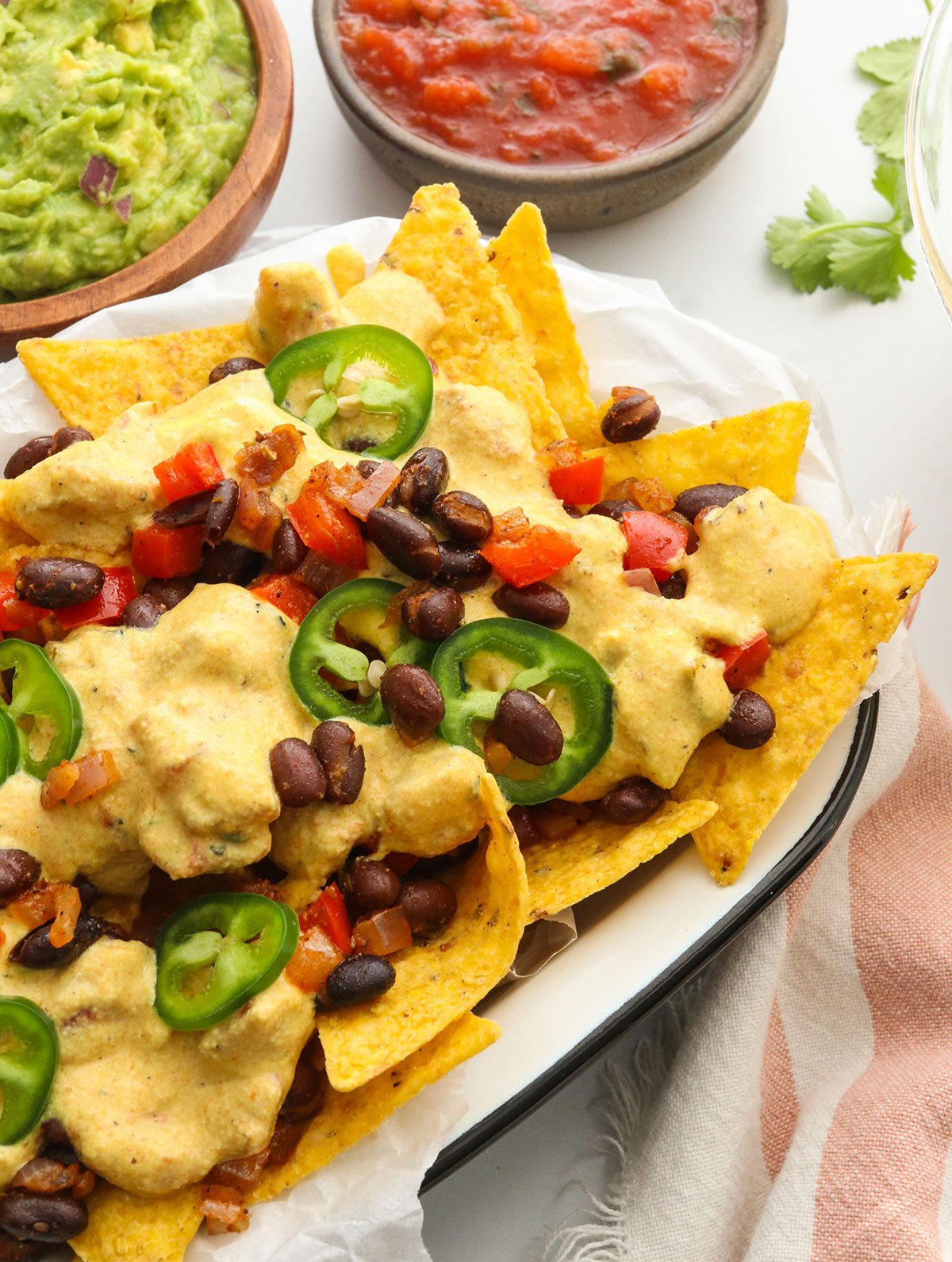 close up of vegan nachos topped with queso and jalapenos.